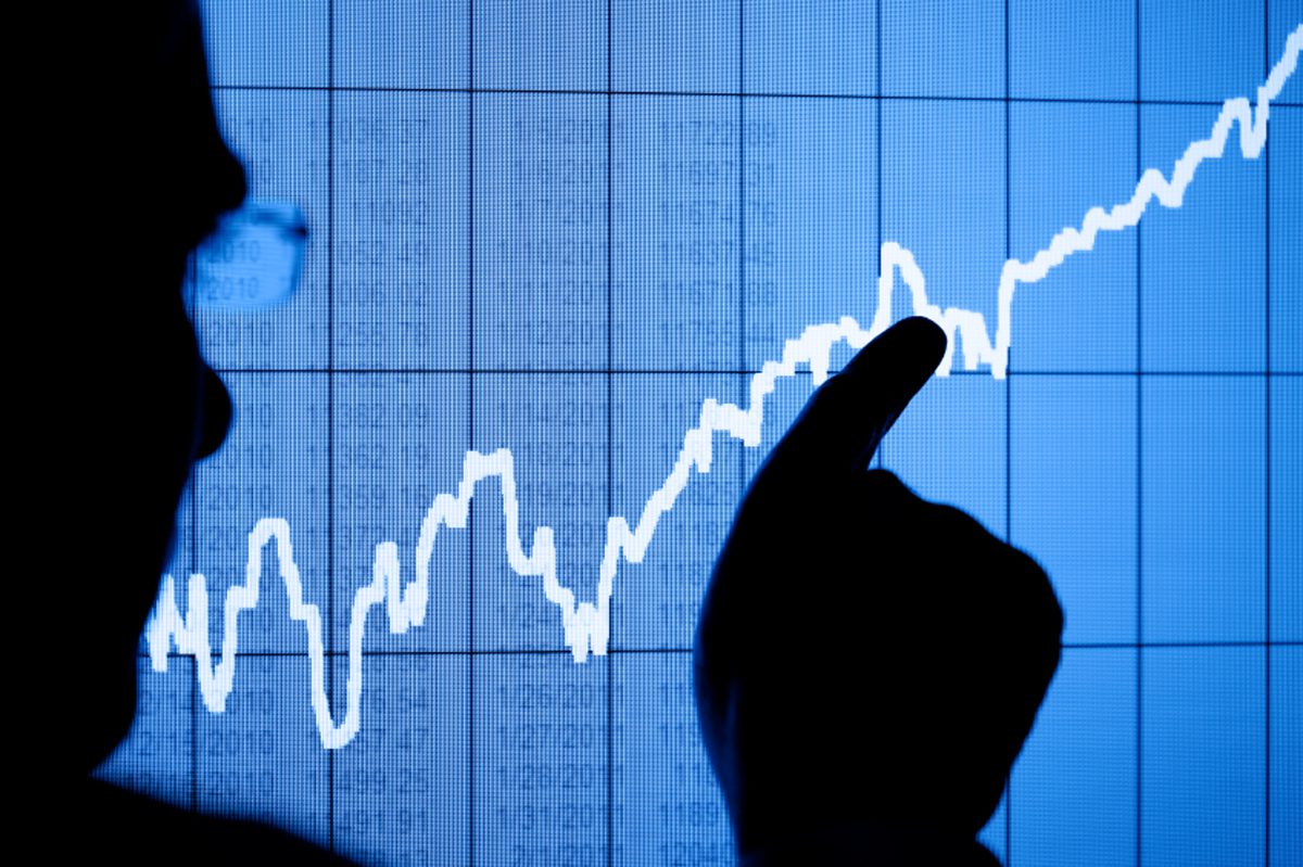 Silhouette of a man pointing to a rising graph on an LCD display. Focus is on the LCD display. Chart created by the photographer.